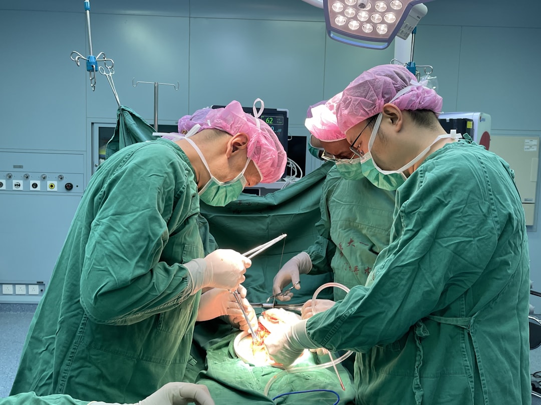 Surgeons in a hospital operating room performing a complex medical procedure with surgical tools and equipment.